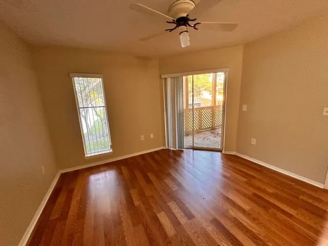 a view of an empty room with wooden floor and a window