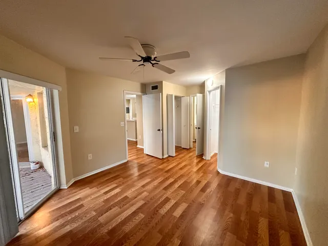 a view of empty room with wooden floor and fan