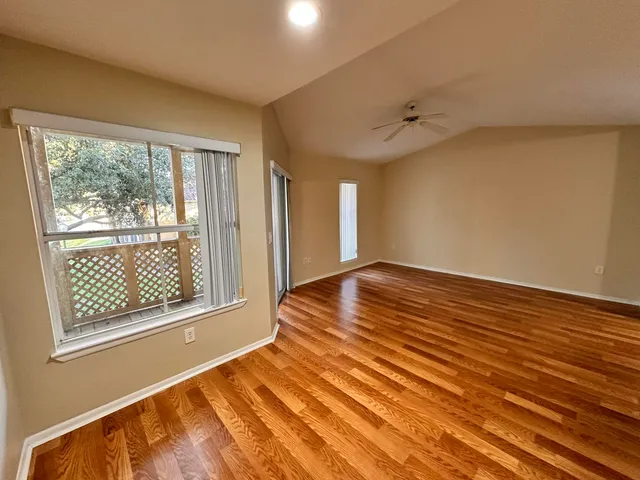 a view of an empty room with wooden floor and a window