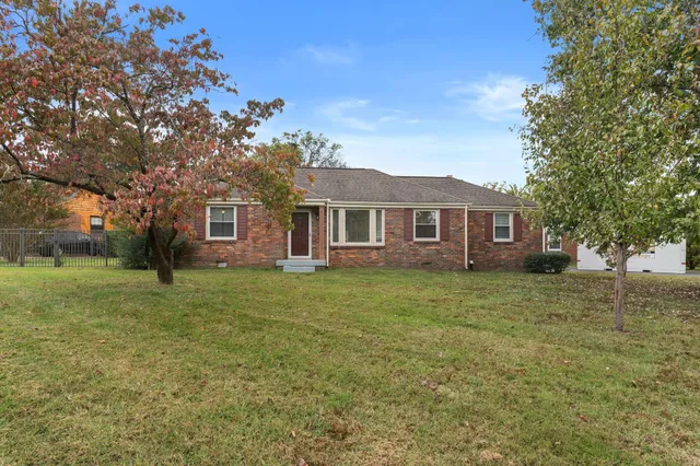 a view of a yard in front of a house with large trees