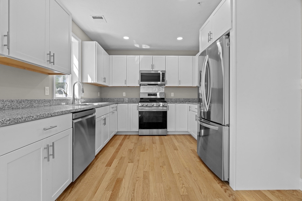 a kitchen with wooden floors stainless steel appliances and a counter top