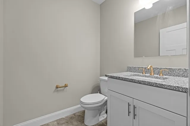a bathroom with a granite countertop toilet sink and mirror