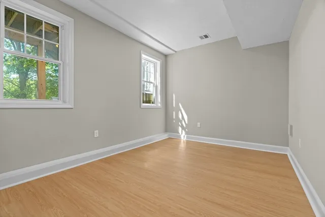 a view of an empty room with wooden floor and windows