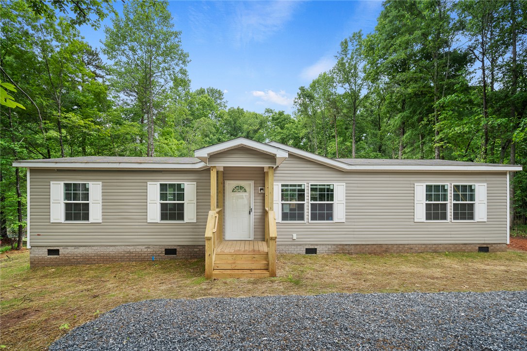 This inviting home offers classic siding and a welcoming porch, nestled among lush trees.
