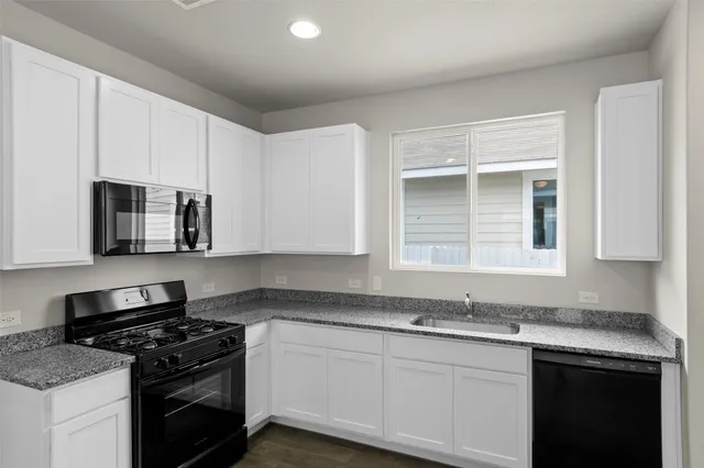 a kitchen with stainless steel appliances granite countertop white cabinets and a stove top oven