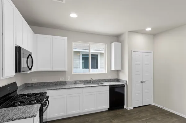 a kitchen with granite countertop white cabinets stainless steel appliances and a sink