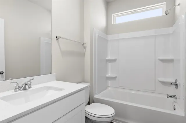 a bathroom with a bathtub shower sink vanity mirror and toilet