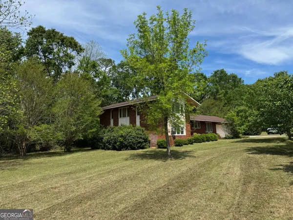 a view of house with yard and trees in the background