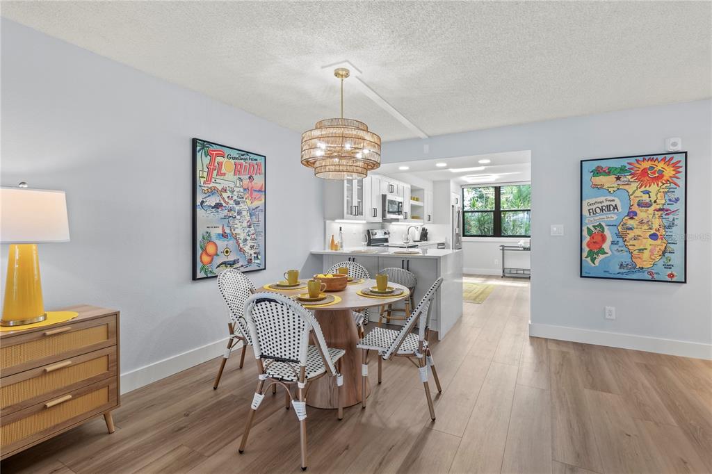 609 Bayport Way, Unit 609 Longboat Key, FL 34228 - Photo 18 of 77 a dining room with wooden floor a chandelier a wooden table and chairs