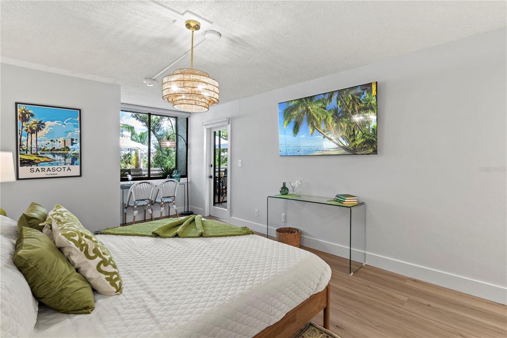 609 Bayport Way, Unit 609 Longboat Key, FL 34228 - Photo 28 of 77 a bedroom with a bed and a chandelier