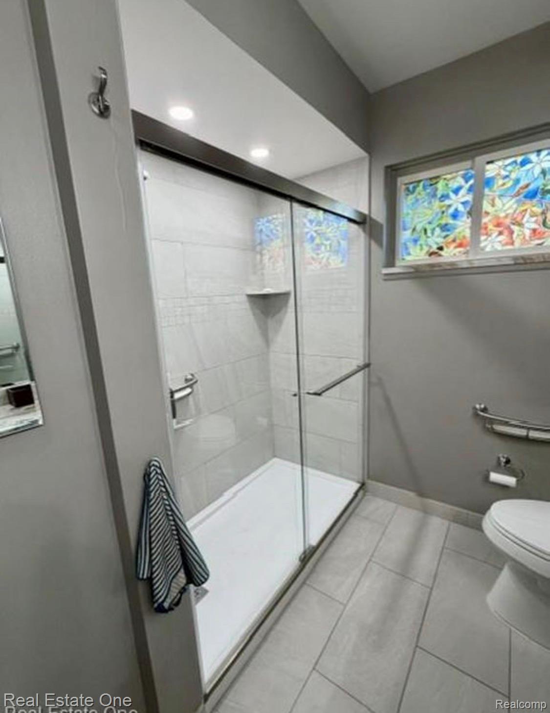 1115 Torpey Road Troy, MI 48083 - Photo 28 of 38 Tiled shower enclosure with glass sliding doors, integrated shelving, and recessed lighting