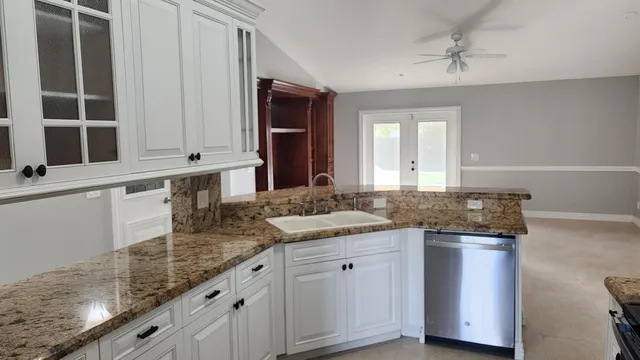 a kitchen with granite countertop a sink and white cabinets