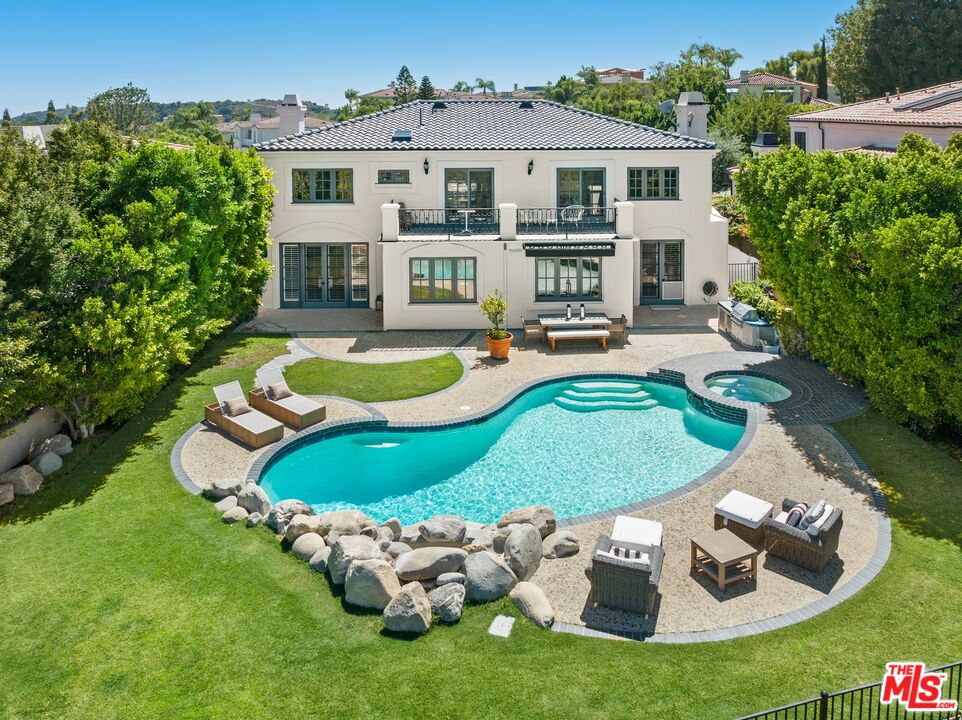 12519 Promontory Road Los Angeles, CA 90049 - Photo 3 of 10 a view of a white house with a swimming pool and a yard