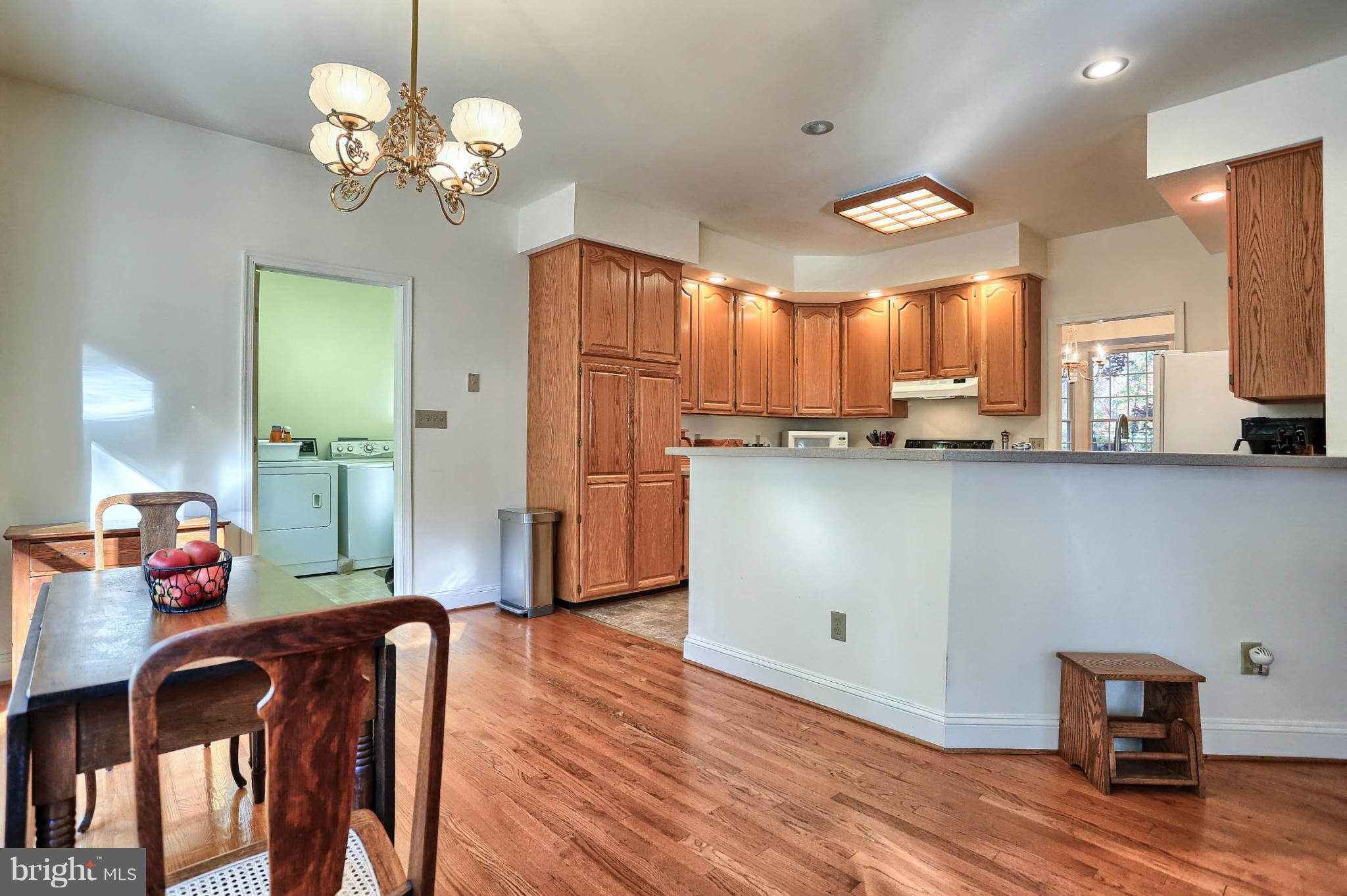 4905 Teen Barnes Road Frederick, MD 21703 - Photo 11 of 30 a kitchen with stainless steel appliances granite countertop a refrigerator a sink dishwasher a stove and a dining table with wooden floor