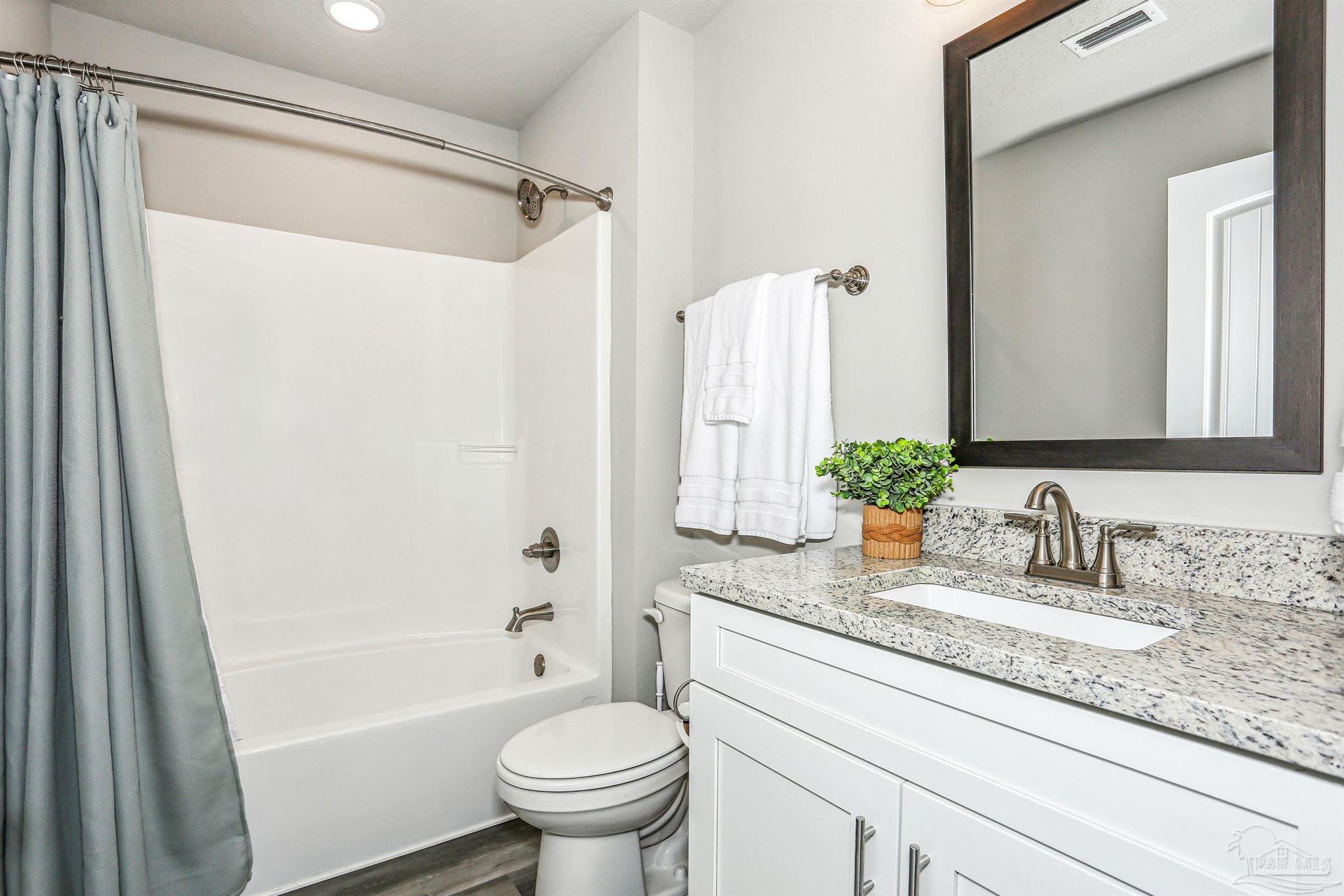 3494 Doyle Hawkins Road Navarre, FL 32566 - Photo 26 of 30 a bathroom with a granite countertop sink toilet and shower