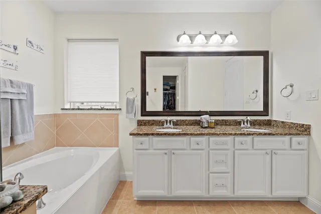 a bathroom with a granite countertop bathtub a sink and a mirror