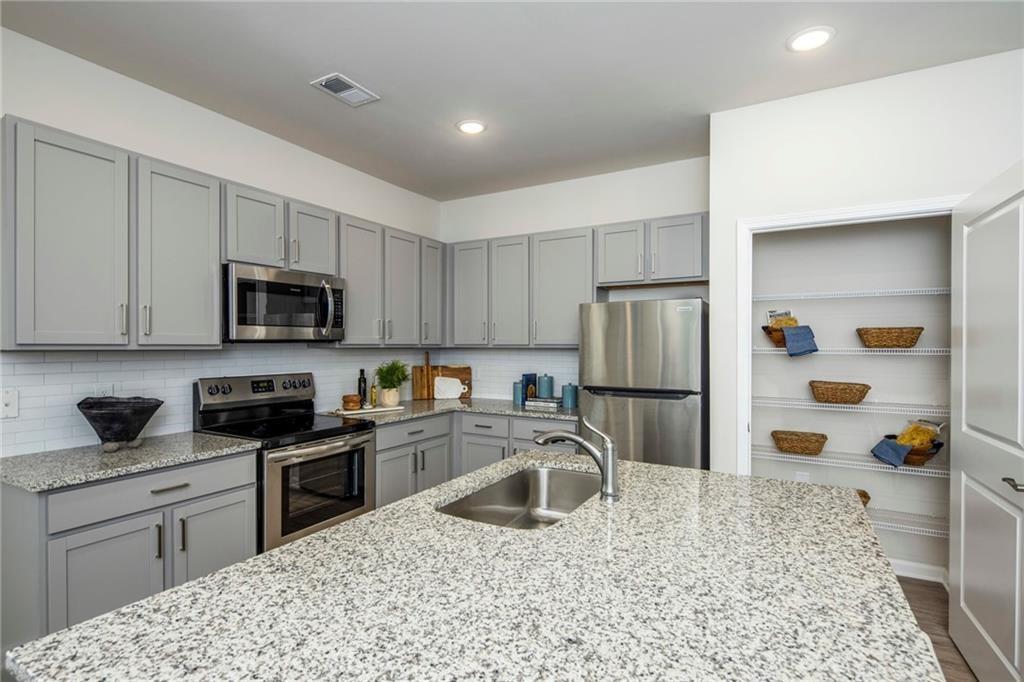 100 Cottage Way, Unit CARAWAY Hampton, GA 30228 - Photo 24 of 44 a kitchen with stainless steel appliances granite countertop a sink stove and refrigerator