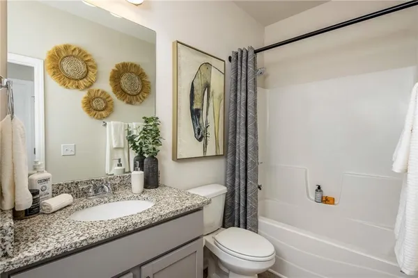 a bathroom with a granite countertop sink mirror vanity and toilet