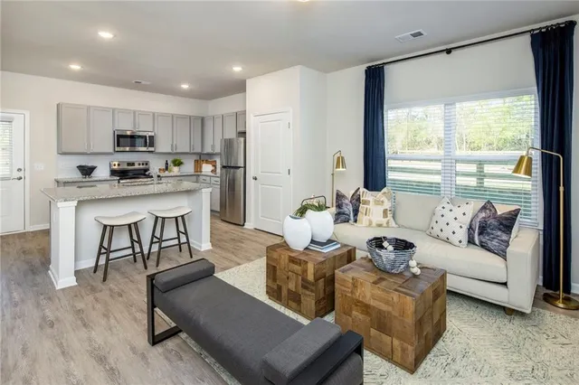 a living room with furniture kitchen view and a large window