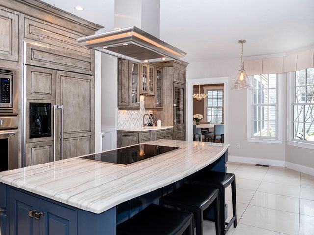 a large kitchen with granite countertop a table chairs and a refrigerator