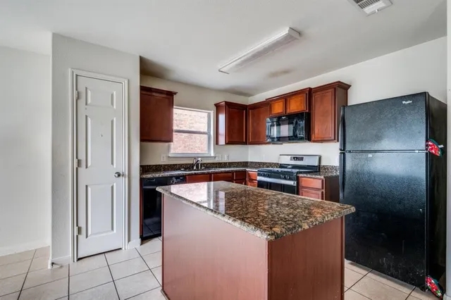 a kitchen with stainless steel appliances granite countertop a refrigerator a stove a sink and a microwave