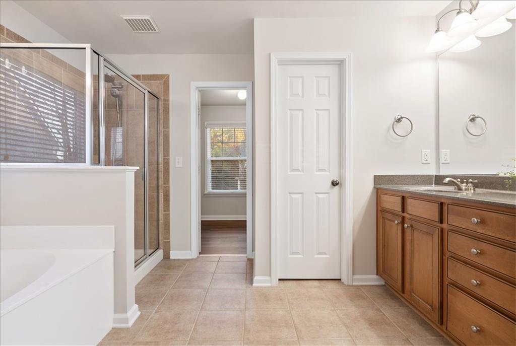 4740 Shiloh Crossing Way Cumming, GA 30040 - Photo 17 of 25 a spacious bathroom with a granite countertop sink a mirror and a shower