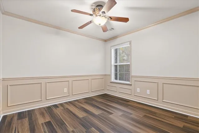 a view of an empty room with chandelier fan and wooden floor