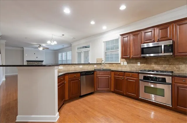 a kitchen with stainless steel appliances granite countertop a stove top oven a sink dishwasher a refrigerator and a microwave oven on the blue kitchen countertops