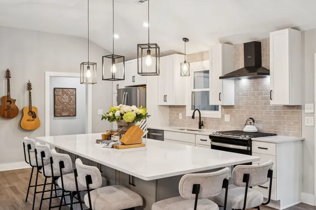 a kitchen with stainless steel appliances kitchen island granite countertop a table chairs and a refrigerator