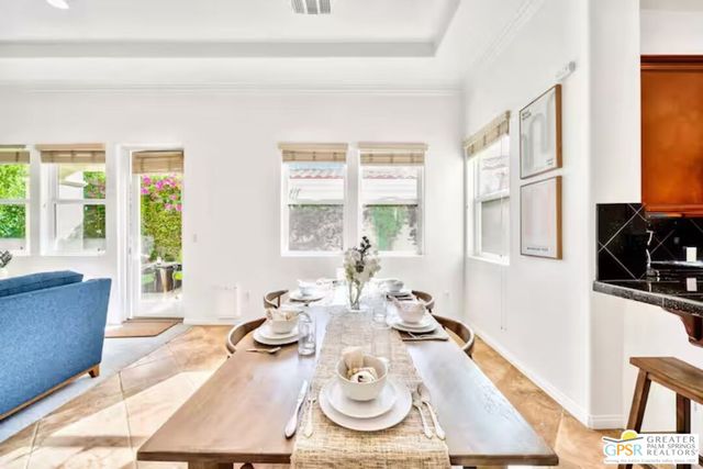 a living room with lots of tables a chandelier and kitchen view