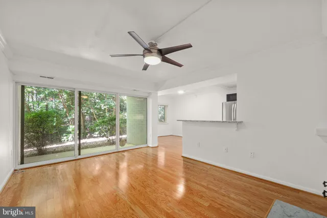 a view of an empty room with a window and wooden floor