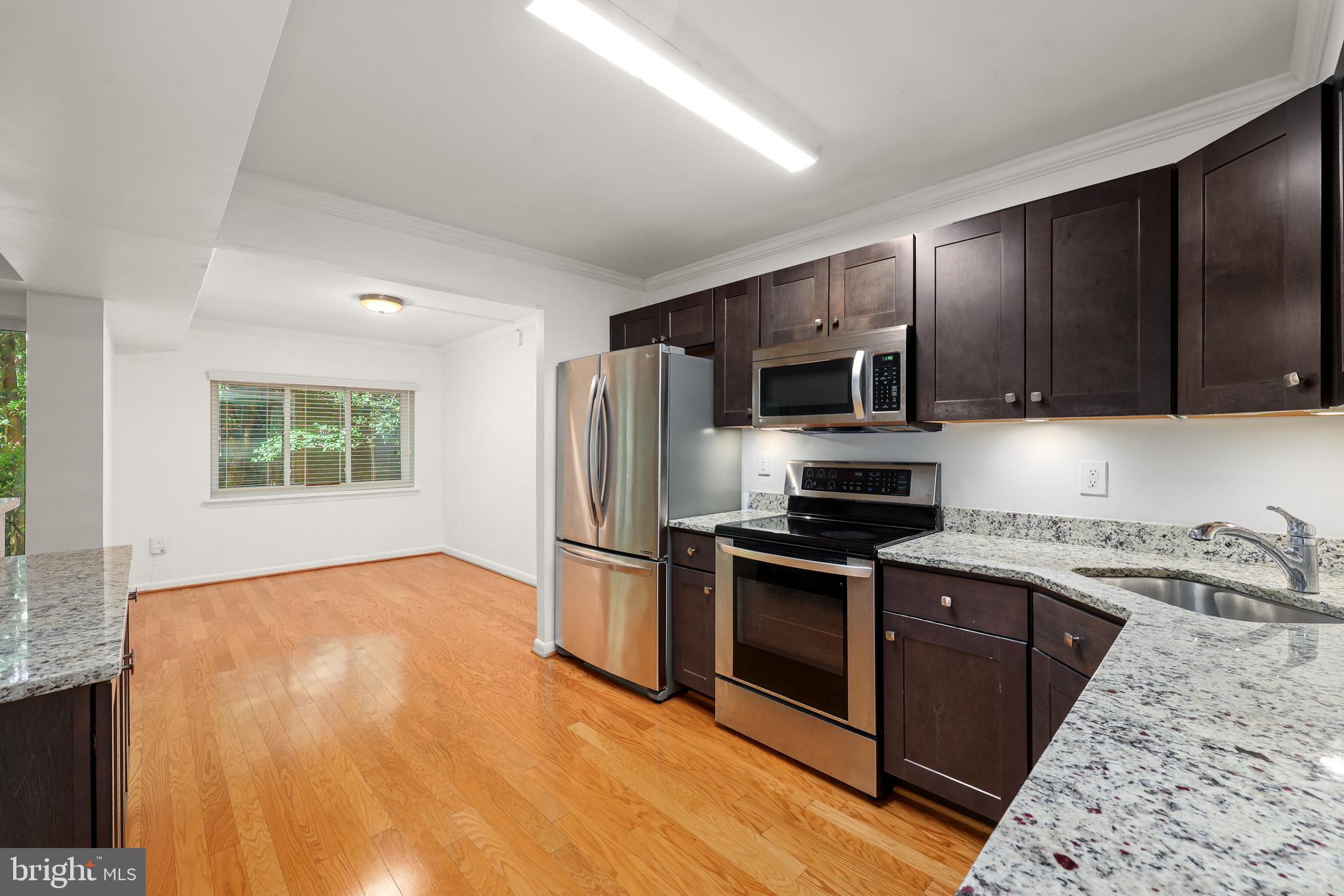 11721 Karbon Hill Court, Unit T2 Reston, VA 20191 - Photo 17 of 31 a kitchen with granite countertop wooden floors stainless steel appliances and a window