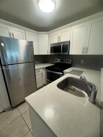 a kitchen with a sink a refrigerator and cabinets
