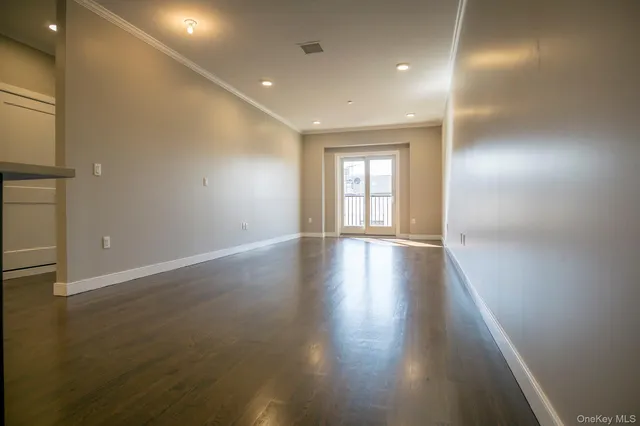 an empty room with wooden floor and windows with curtains