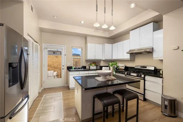 a kitchen with stainless steel appliances granite countertop a stove a refrigerator a sink a stove and white cabinets