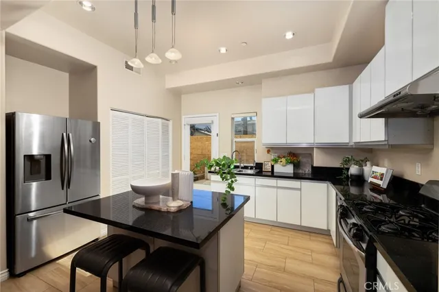 a kitchen with stainless steel appliances a dining table chairs stove refrigerator and cabinets