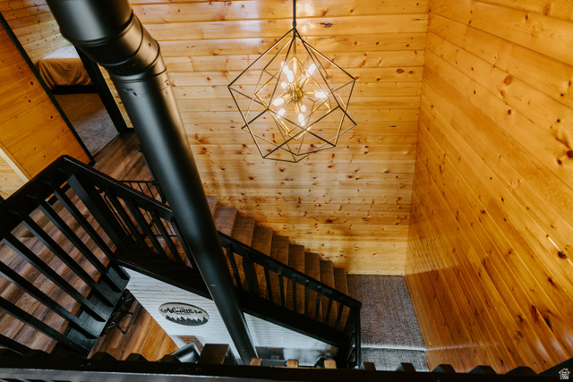 1413 Basel Drive Midway, UT 84049 - Photo 75 of 137 Stairs with hanging lights, wood walls, a wood stove, and a high ceiling