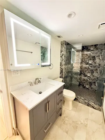 a view of a patio with a table and chairs under an umbrella with large trees