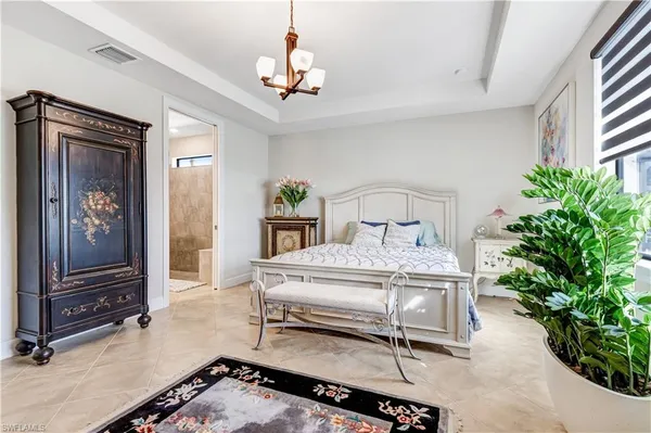 a bedroom with a bed and a potted plant on the dresser