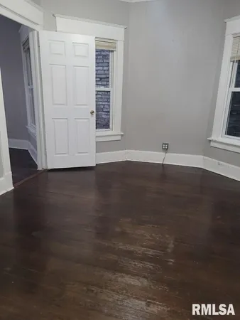 an empty room with wooden floor and window