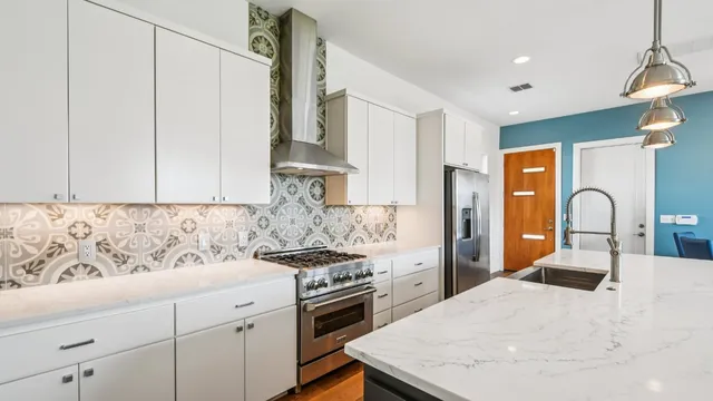 a kitchen with stainless steel appliances a stove a sink a refrigerator white cabinets and wooden floor