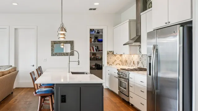 a kitchen with stainless steel appliances granite countertop a refrigerator a stove and a sink with wooden floor