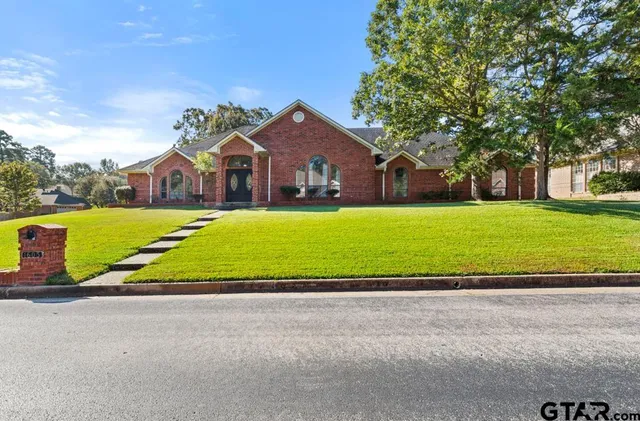 a view of an house with a big yard and large trees