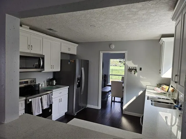 a kitchen with stainless steel appliances kitchen island granite countertop a refrigerator stove and sink
