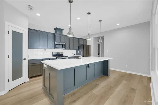 a kitchen with kitchen island a sink stainless steel appliances and cabinets