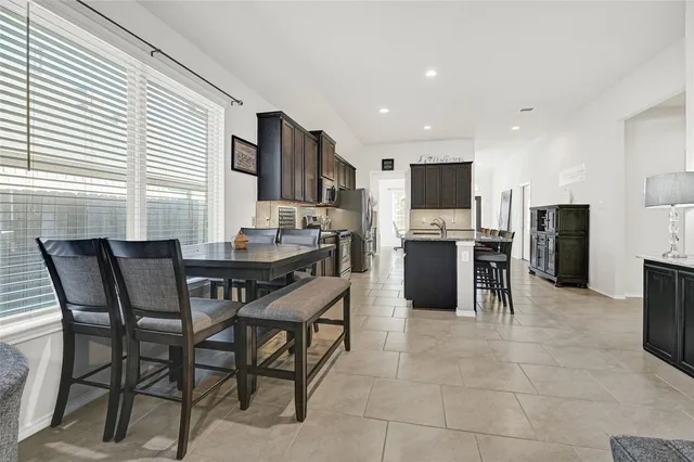 a kitchen with stainless steel appliances granite countertop a stove top oven a sink dishwasher a dining table and chairs with wooden floor