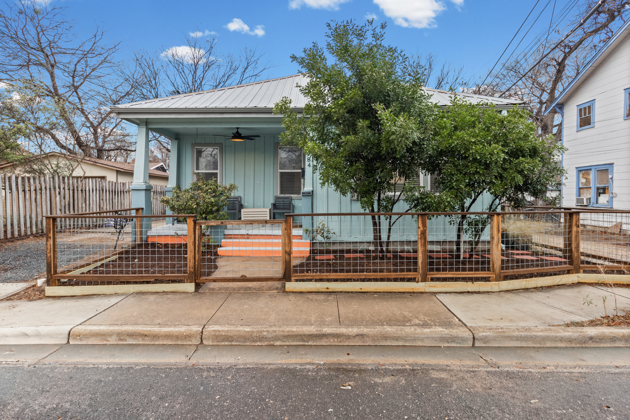 View of front of home featuring covered porch, board and batten siding, a metal roof, a gate, and a fenced front yard