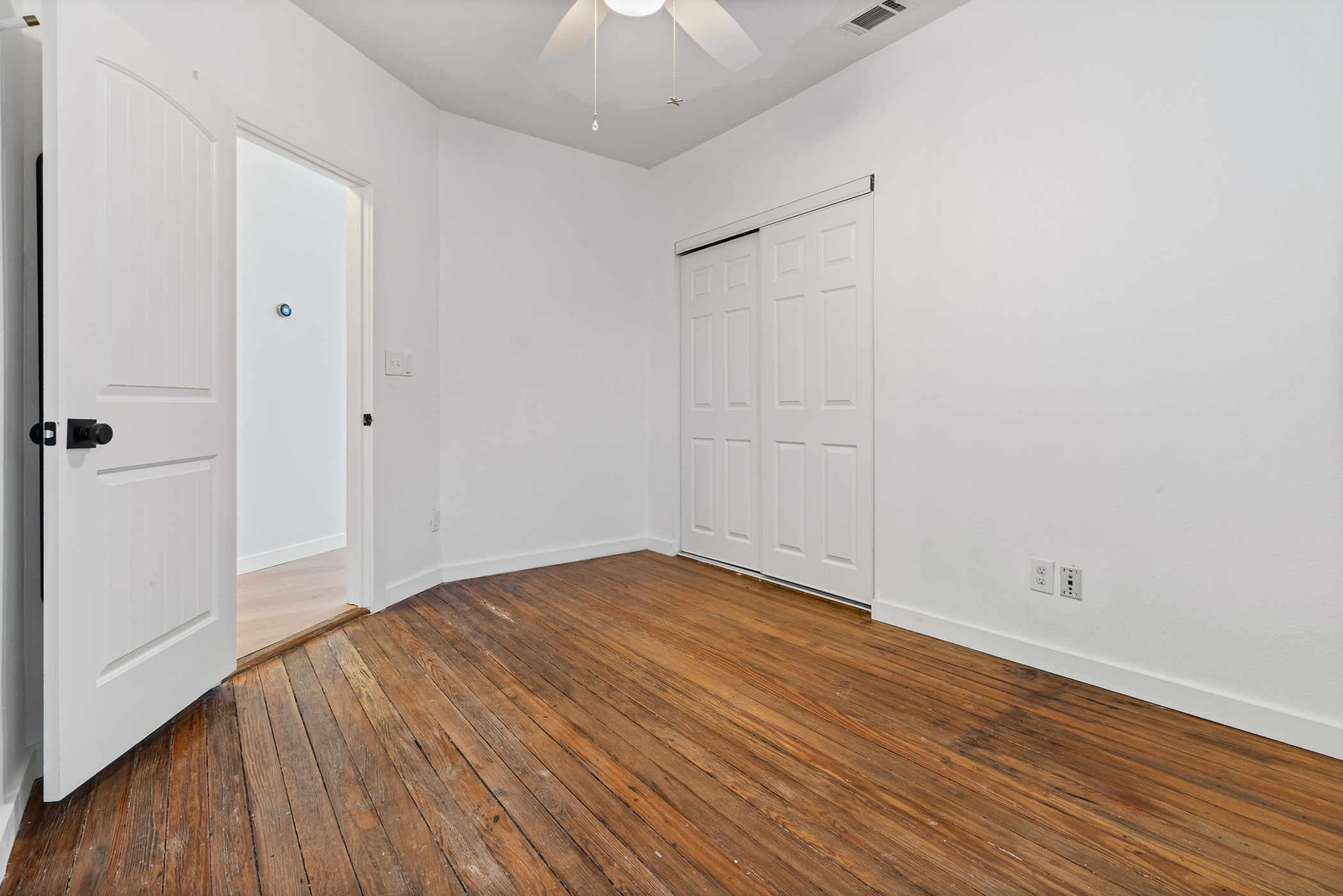 84 Waller Street Austin, TX 78702 - Photo 11 of 22 Unfurnished bedroom featuring dark wood finished floors, ceiling fan, and a closet
