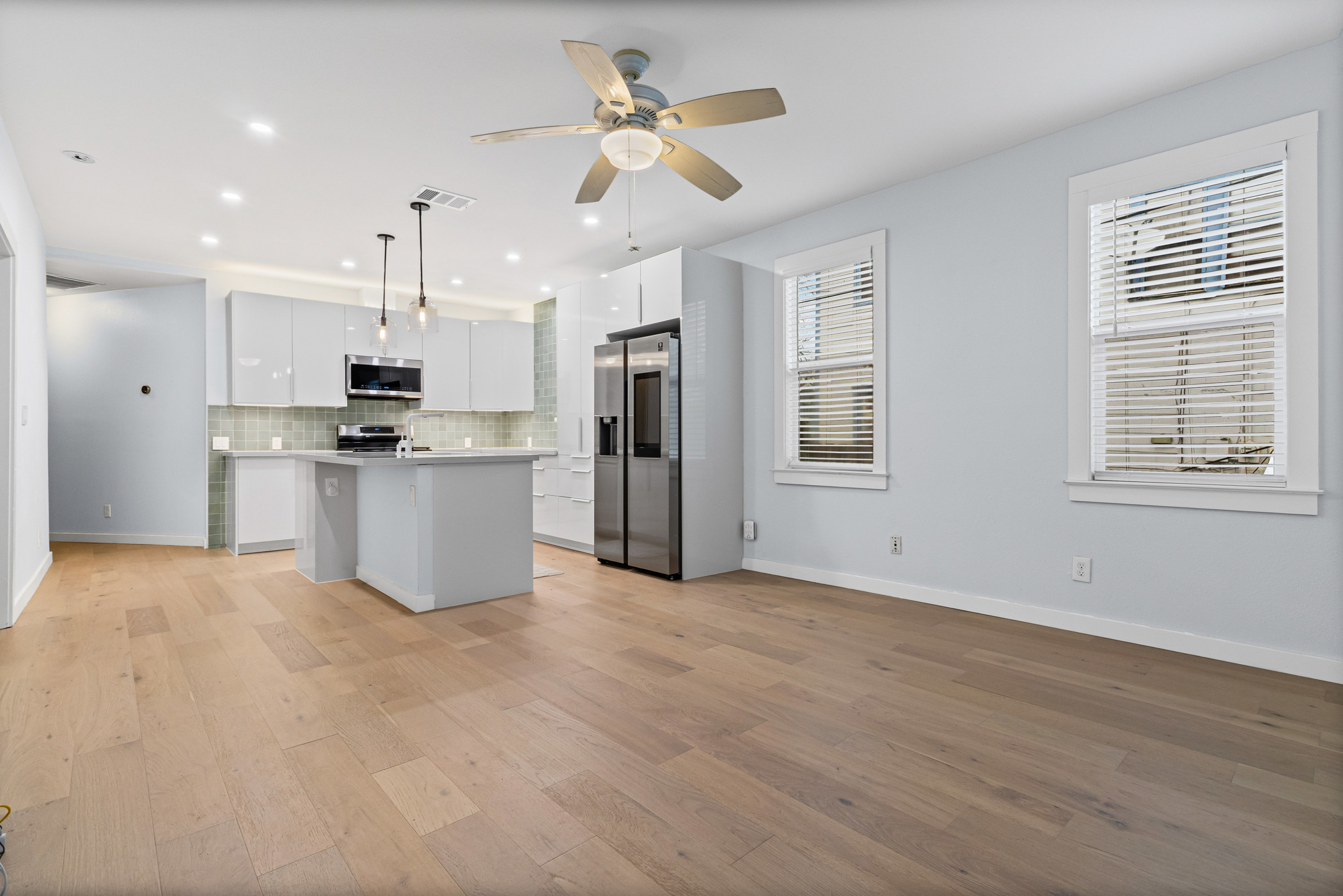 84 Waller Street Austin, TX 78702 - Photo 4 of 22 Kitchen featuring a kitchen island with sink, light countertops, appliances with stainless steel finishes, white cabinetry, and recessed lighting