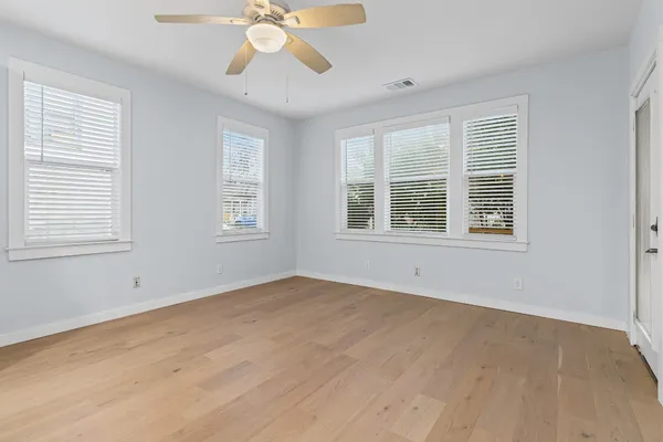 a view of an empty room with a window and wooden floor
